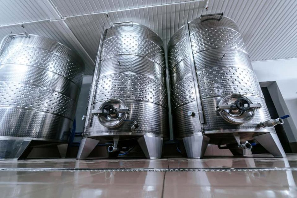 Alignement de plusieurs modèles de cuve inox sur mesure installés dans un domaine viticole ou une brasserie moderne.