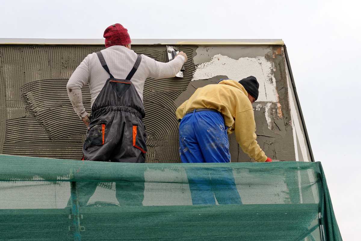 Deux ouvriers sur un échafaudage, travaillant sur un mur